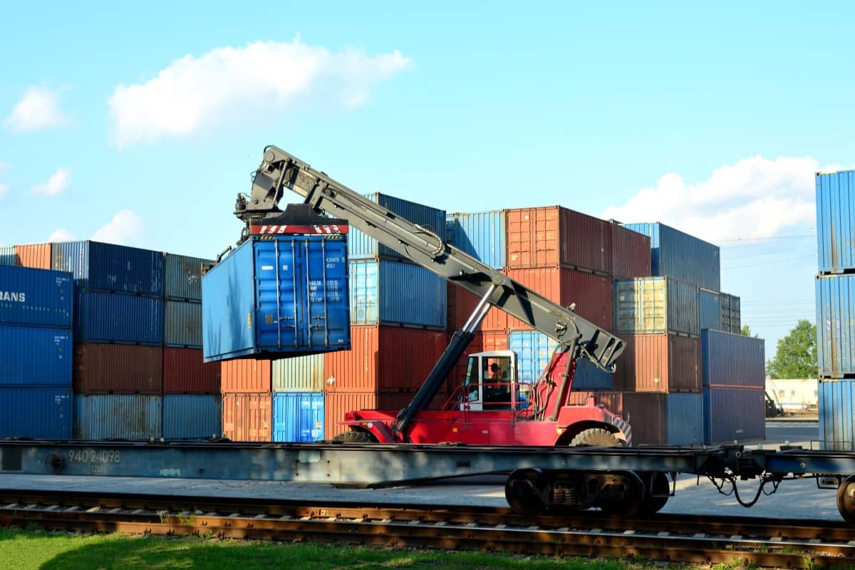 A richtracker loads shipping containers onto a railcar at an intermodal facility