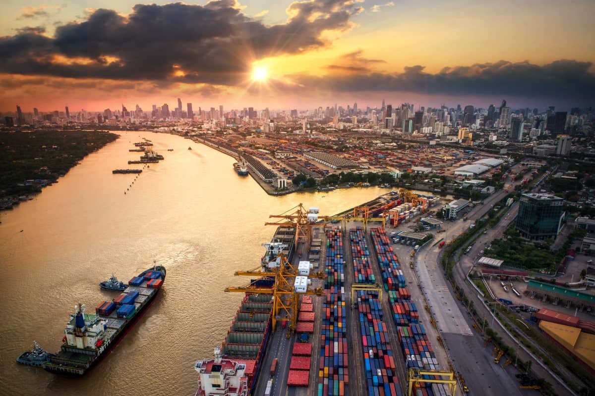 A busy port along a waterway with a large metropolitan city in the background