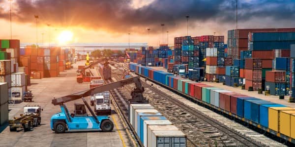 A crane loading freight containers from truck to railcar in a commercial shipping port