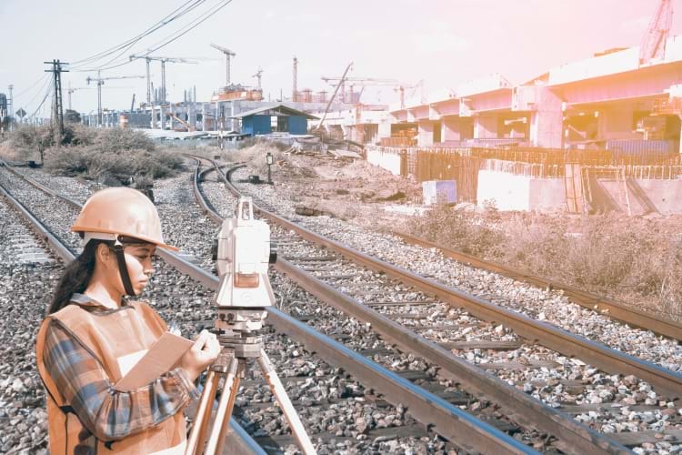 A female engineer using rigorous surveying techniques to analyze railway tracks
