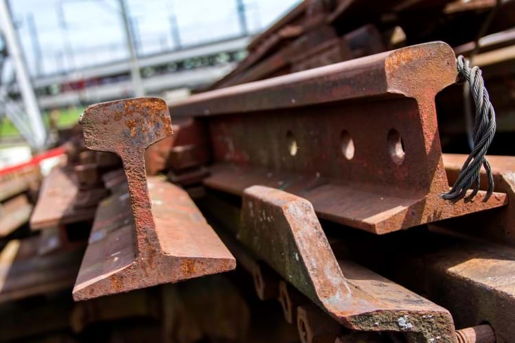 A pile of rusted railroad tracks at a scrap yard