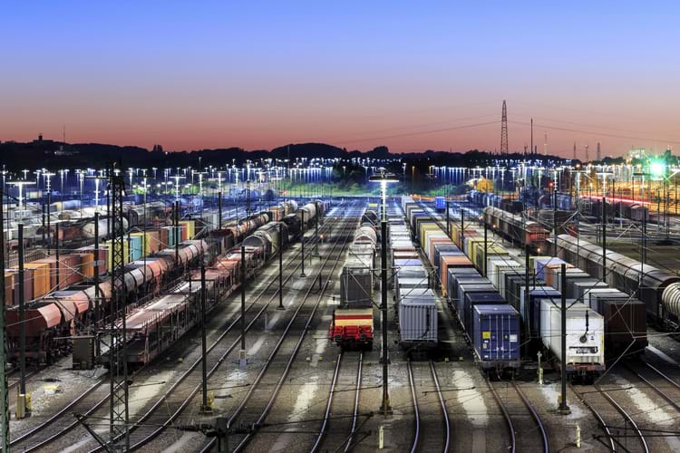 Many different railcars stored at a brightly lit storage yard