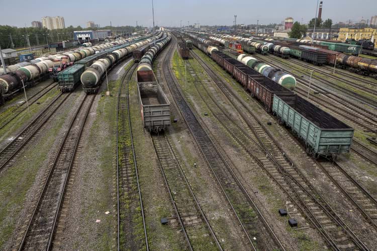 A storage yard with lots of railroad tracks and freight trains during daylight