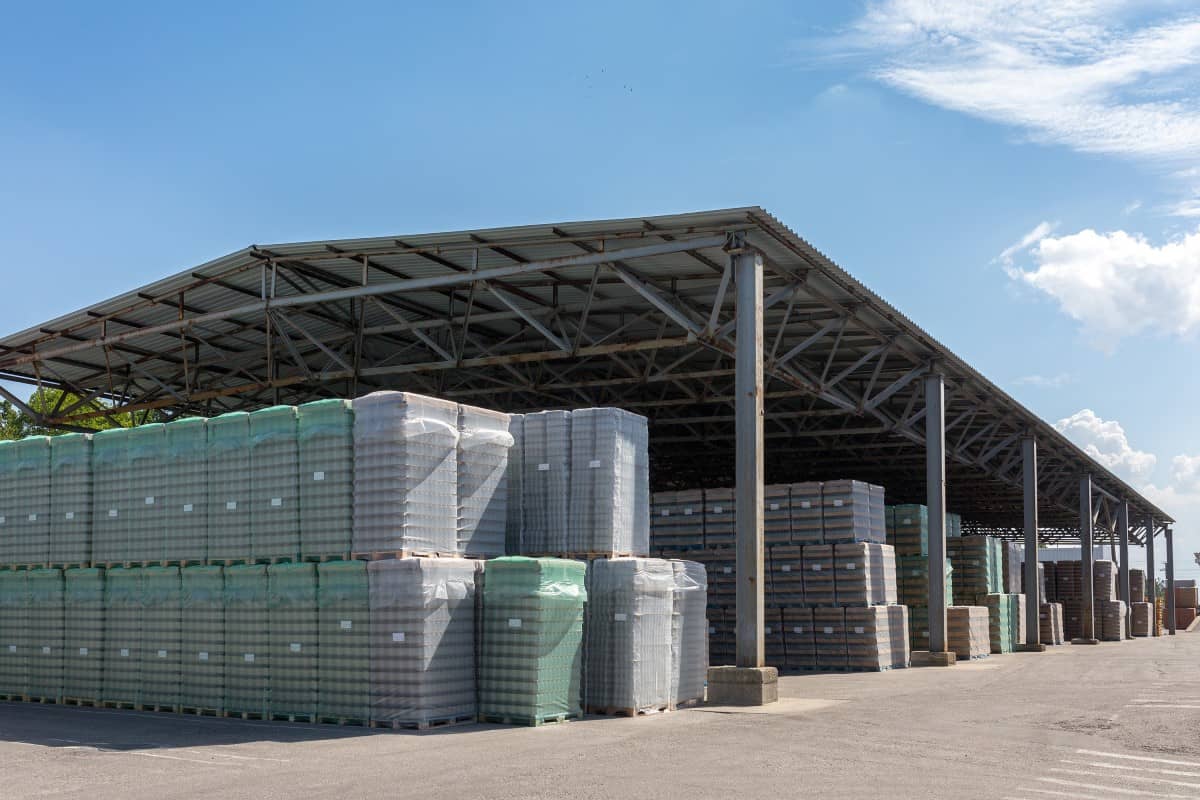 Palletized freight stored under an open-sided warehouse shed