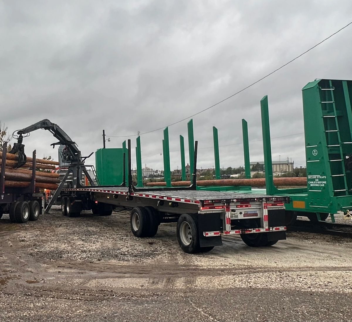 Logs being loaded alongside a bulkhead flatcar